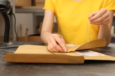 Photo of Post office worker with envelopes at counter indoors, closeup