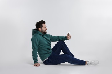 Photo of Happy young man using smartphone on white background