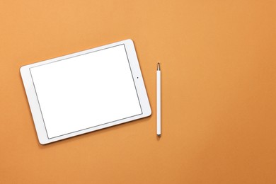 Modern tablet and stylus on orange background, flat lay. Space for text