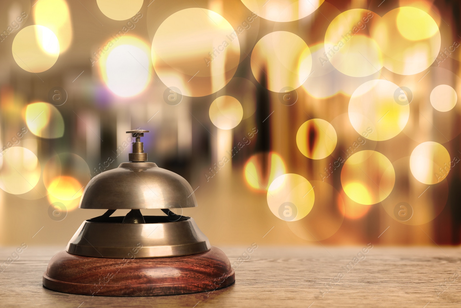 Image of Wooden table with hotel service bell on blurred background. Space for text