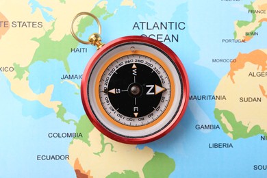 Photo of Compass on world map, top view. Navigation equipment