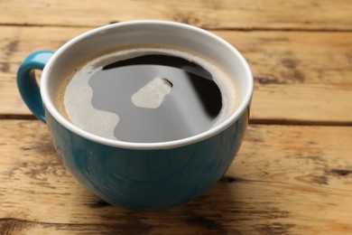 Cup of aromatic coffee on wooden table, closeup