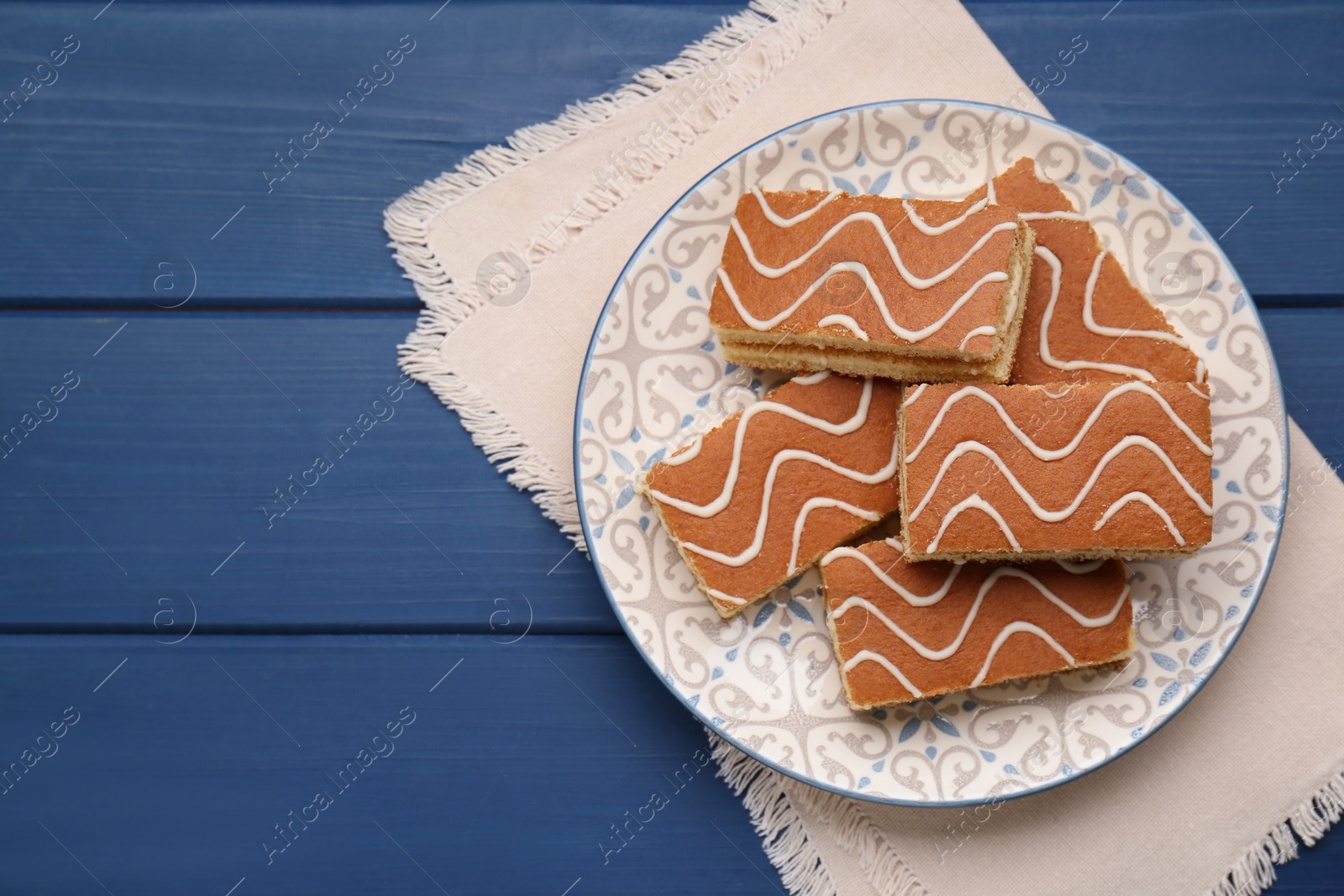 Photo of Tasty sponge cakes on blue wooden table, top view. Space for text