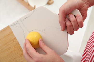 Photo of Man rubbing cutting board with lemon at home, closeup
