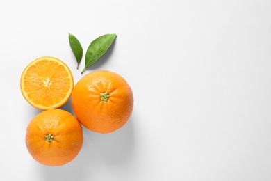 Photo of Juicy oranges and leaves on white background, top view