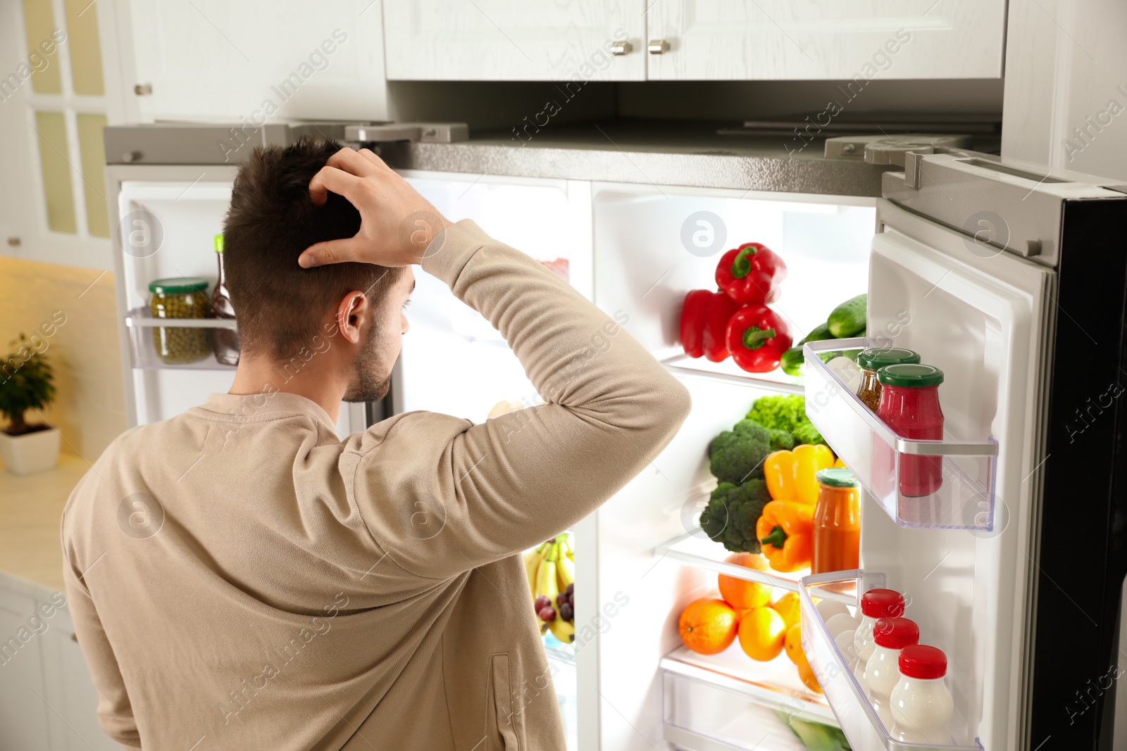 Photo of Young man near open refrigerator in kitchen