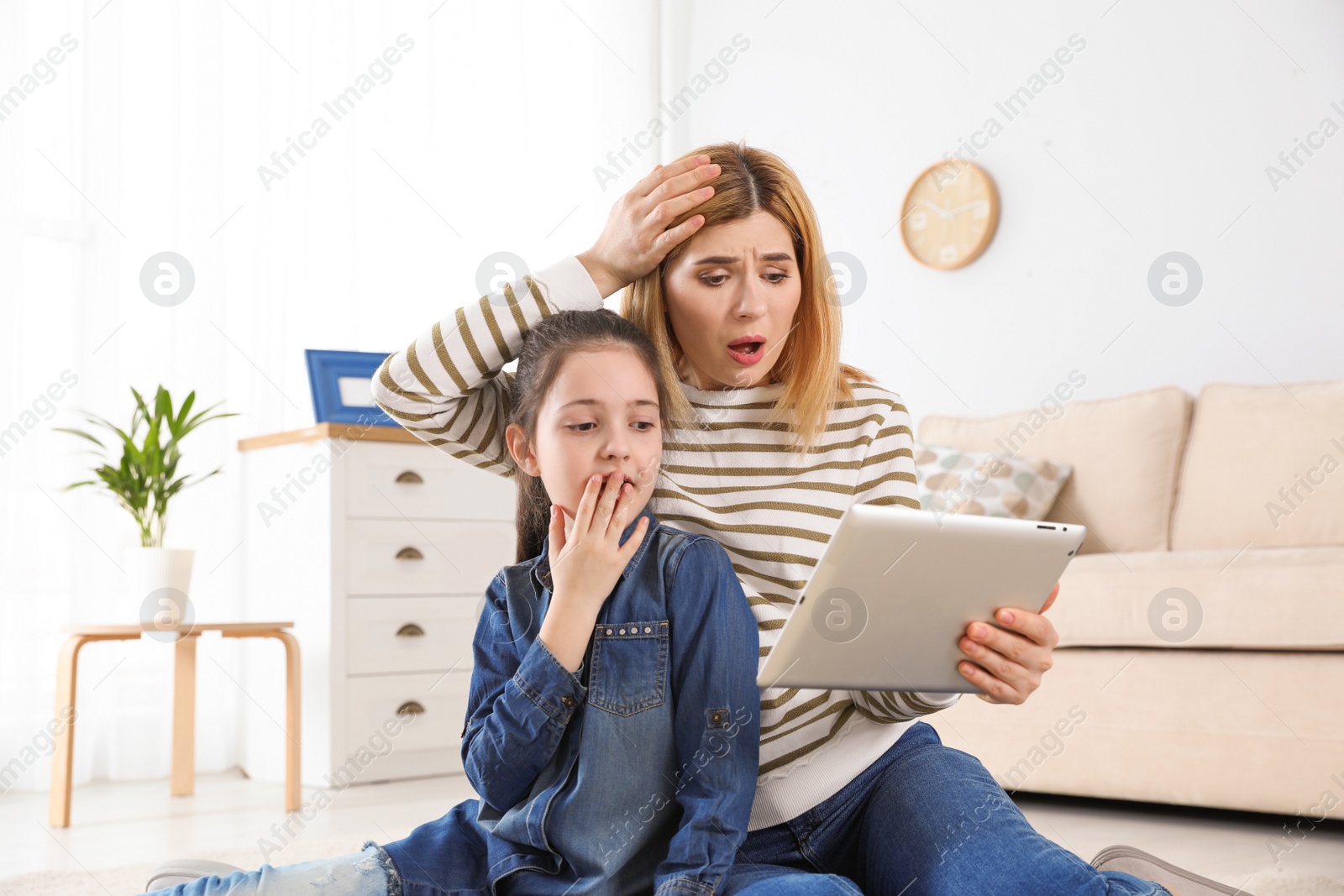 Photo of Mother and her daughter using video chat on tablet at home