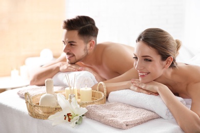 Photo of Young couple with spa essentials in wellness center