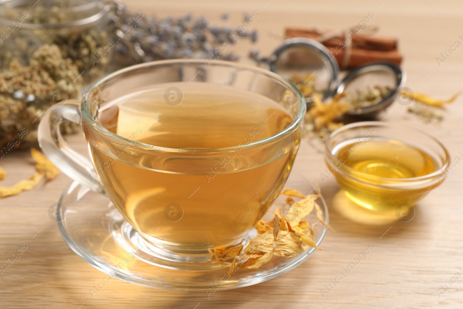 Photo of Freshly brewed tea and dried herbs on wooden table, closeup