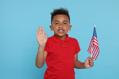 4th of July - Independence Day of USA. Happy boy with American flag on light blue background