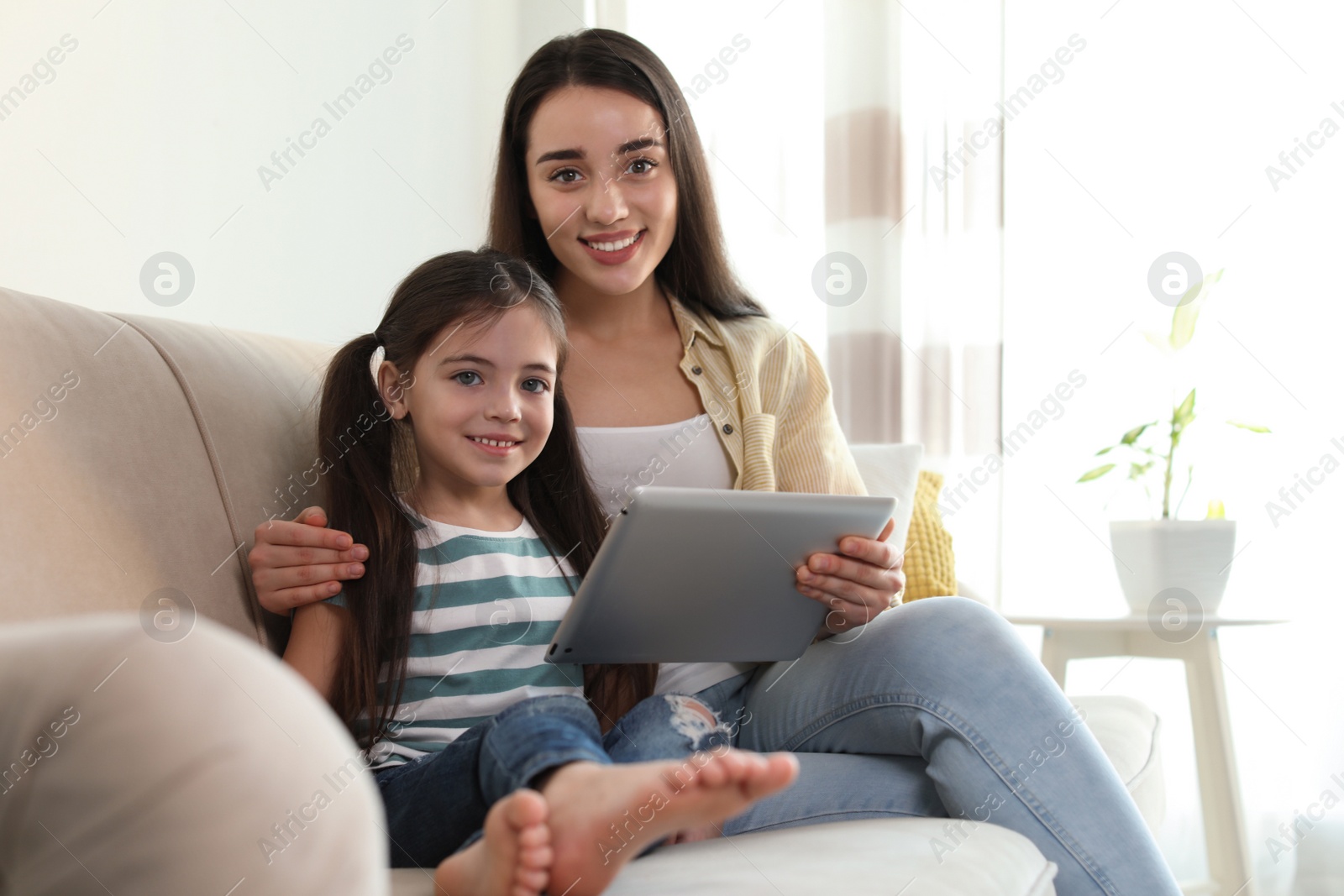 Photo of Mother and daughter reading E-book together at home