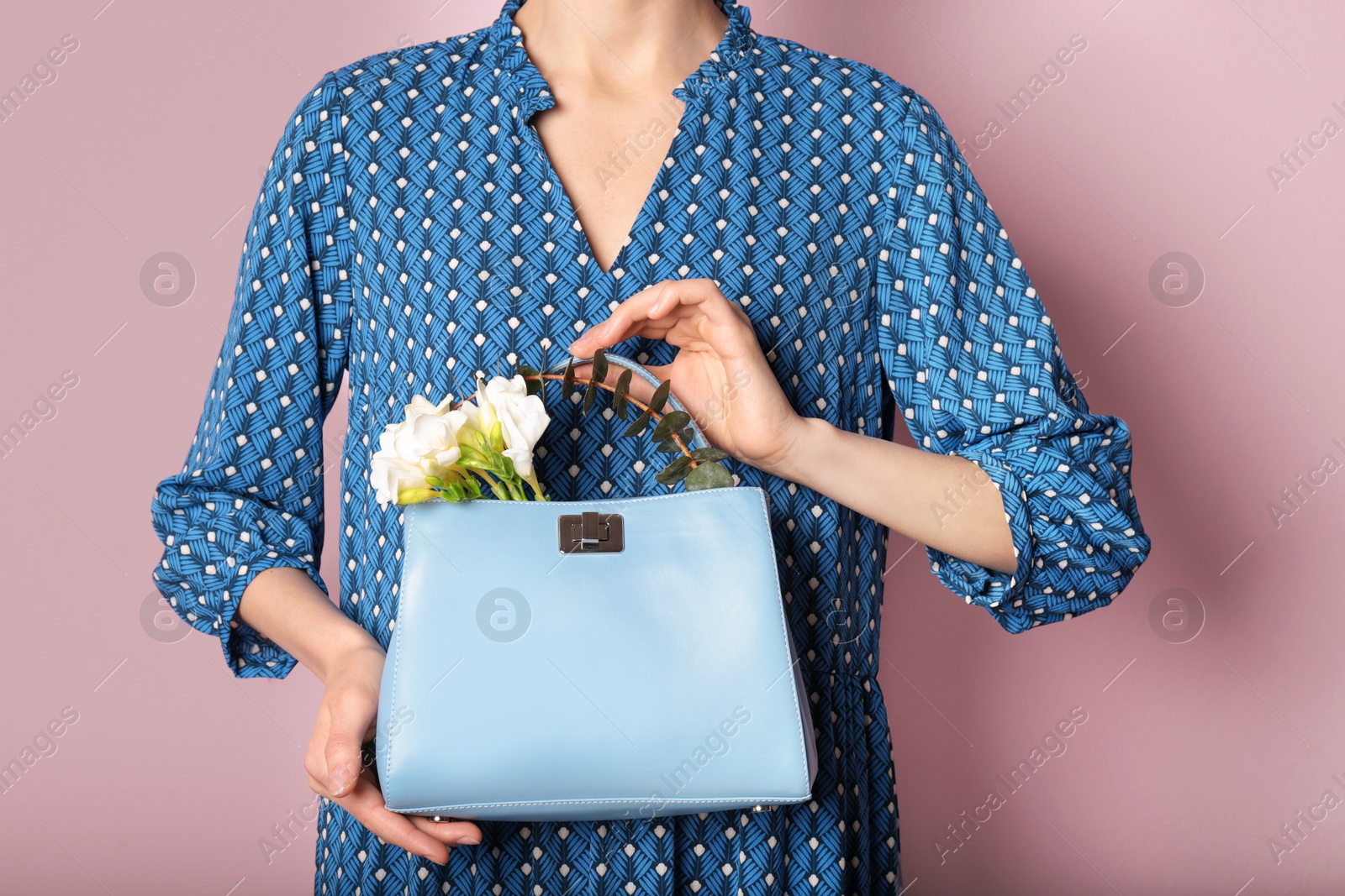 Photo of Stylish woman with handbag and spring flowers against color background, closeup