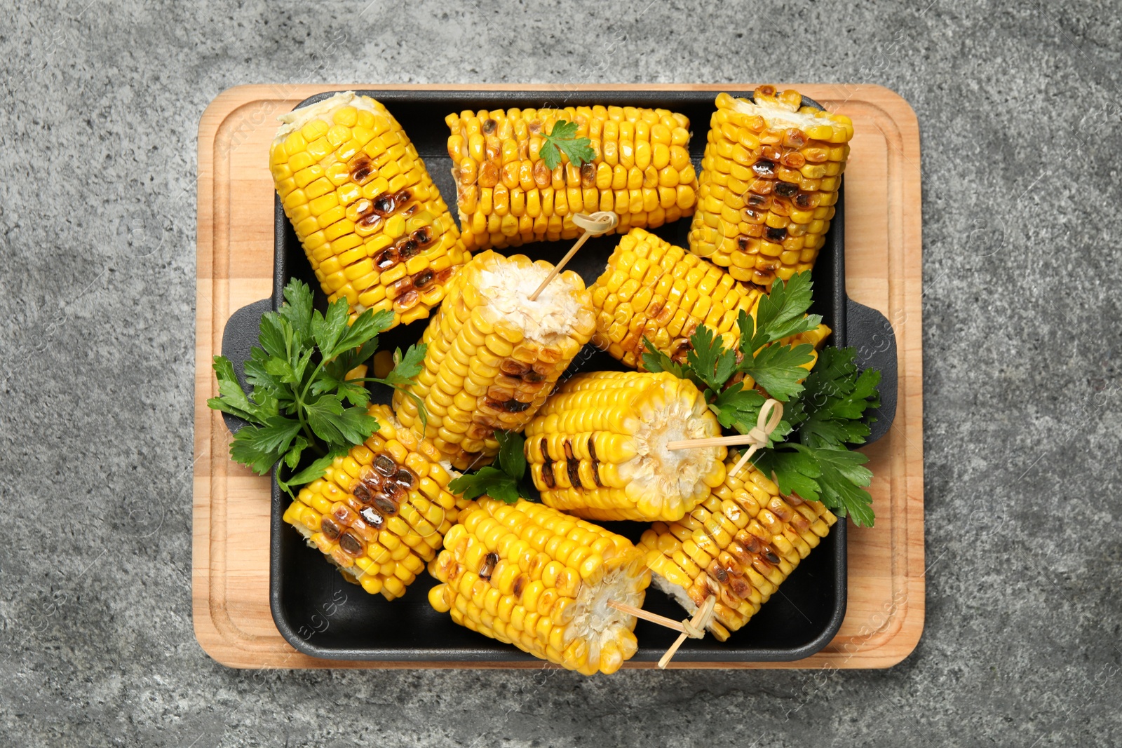 Photo of Tasty grilled corn on grey table, top view
