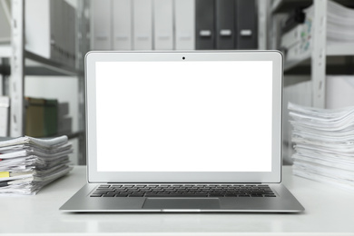 Image of Modern computer with blank screen on table in office. Space for design