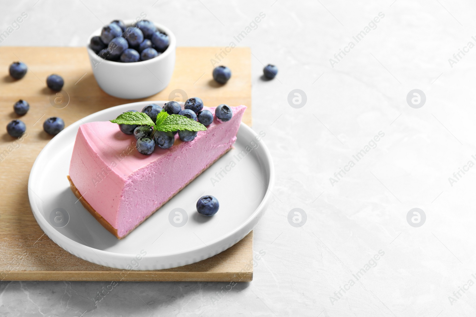 Photo of Plate with tasty cake and blueberries on light table. Space for text