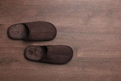 Photo of Pair of brown slippers on wooden floor, top view. Space for text