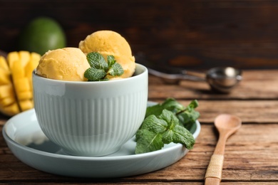 Photo of Delicious mango ice cream served on wooden table, space for text