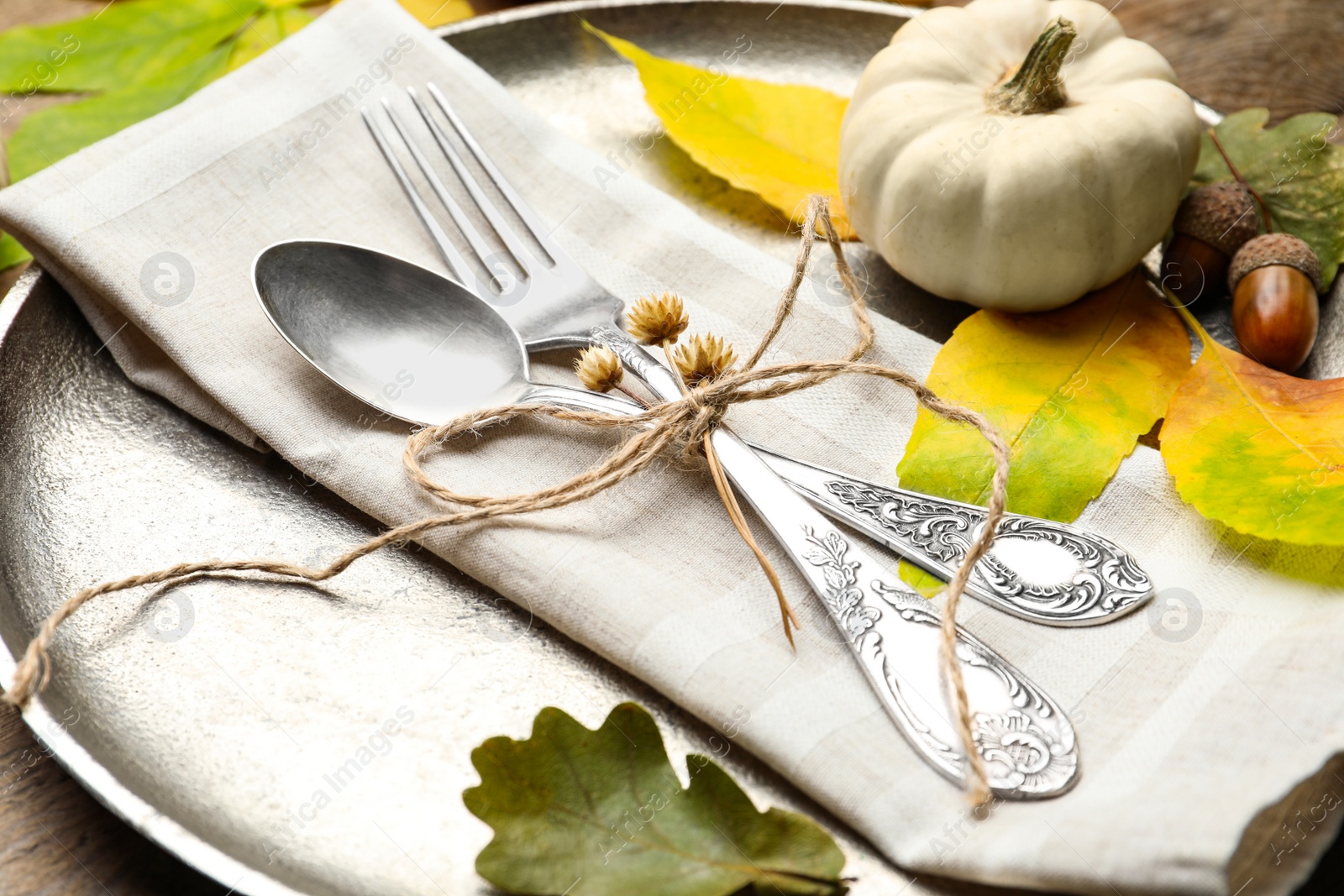 Photo of Autumn place setting with pumpkin and fallen leaves on table, closeup