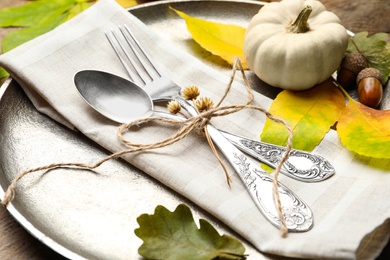 Photo of Autumn place setting with pumpkin and fallen leaves on table, closeup