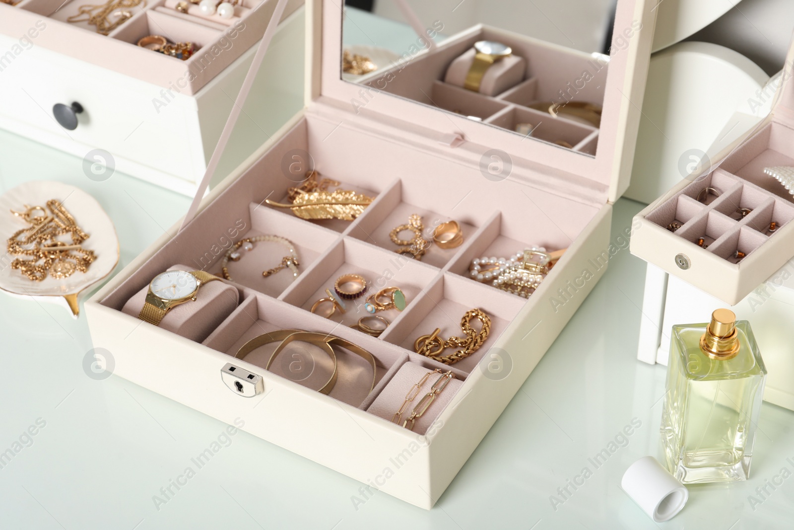 Photo of Elegant jewelry box with beautiful bijouterie and luxury perfume on dressing table