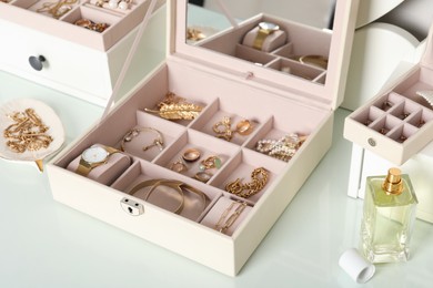 Photo of Elegant jewelry box with beautiful bijouterie and luxury perfume on dressing table