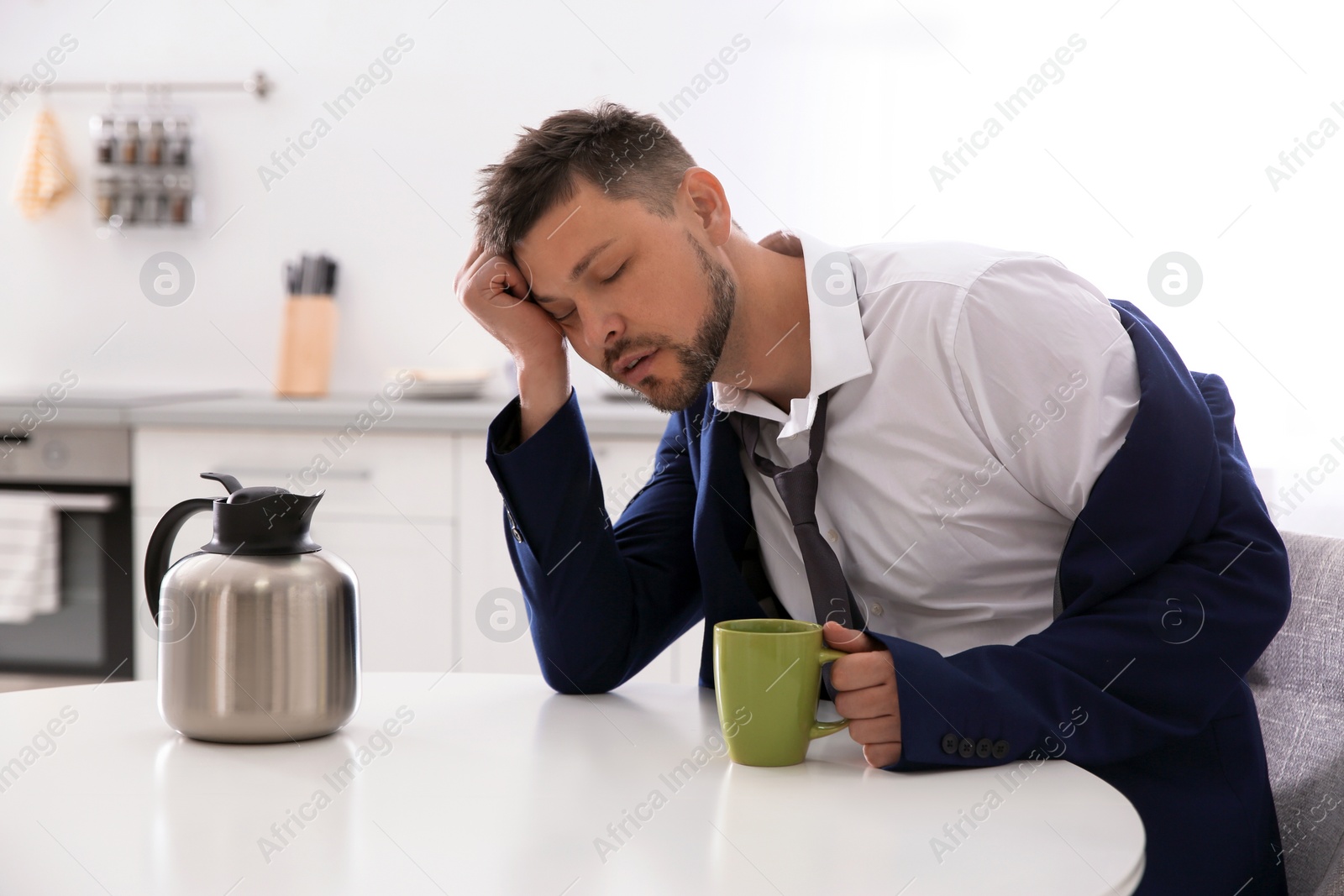 Photo of Sleepy man with cup of drink at home in morning