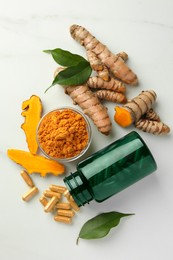 Aromatic turmeric powder, pills and raw roots on white marble table, flat lay
