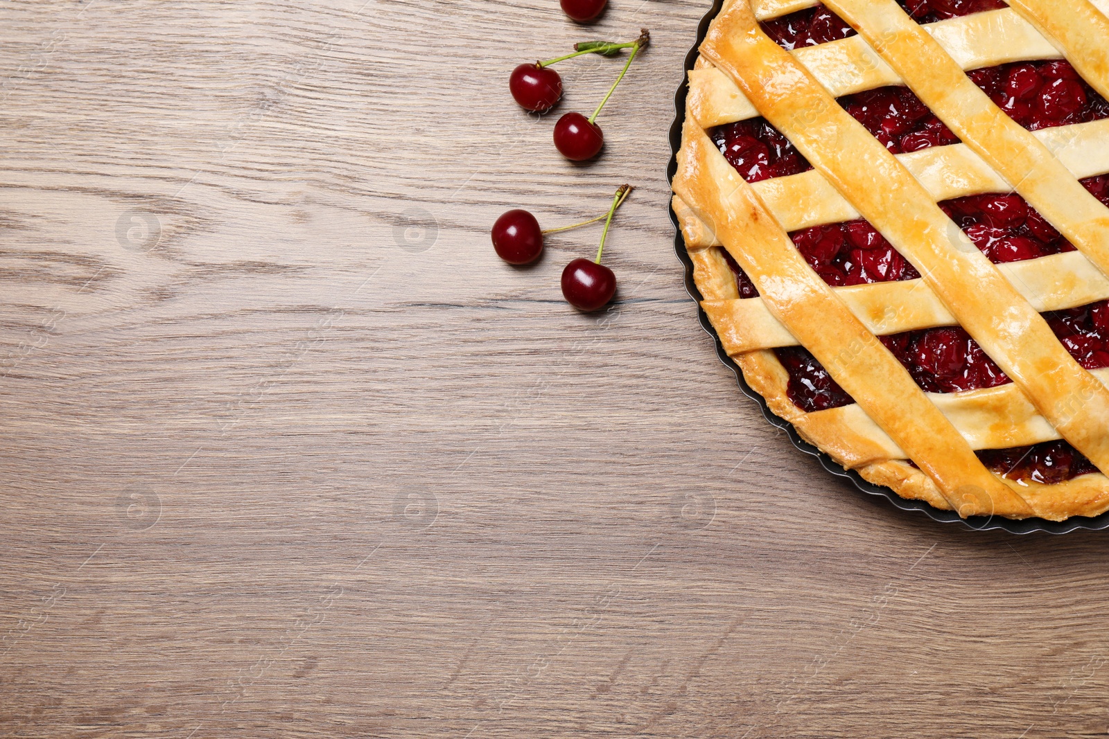 Photo of Delicious fresh pie and cherries on wooden table, flat lay. Space for text