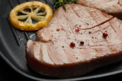 Delicious tuna steak with spices and lemon in grill pan, closeup