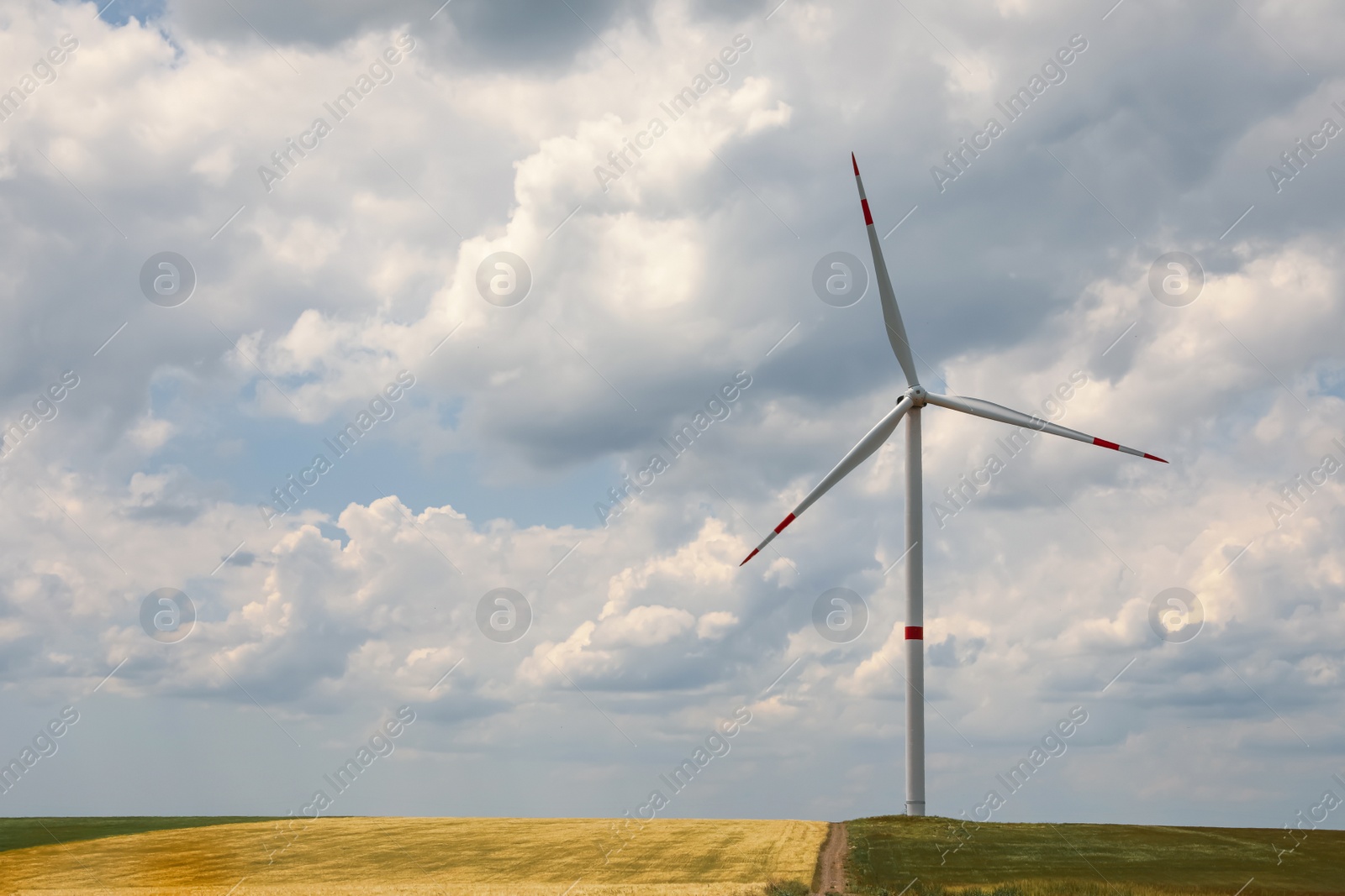 Photo of Modern wind turbine in field on cloudy day. Alternative energy source