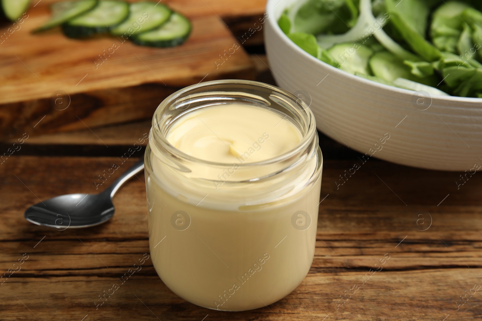 Photo of Jar of delicious mayonnaise and salad on wooden table