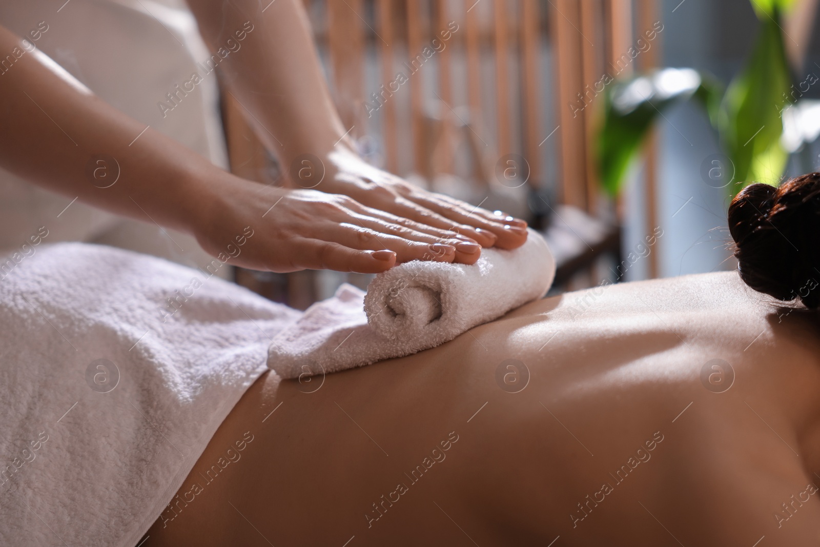 Photo of Spa therapy. Beautiful young woman lying on table during hot towel massage in salon, closeup