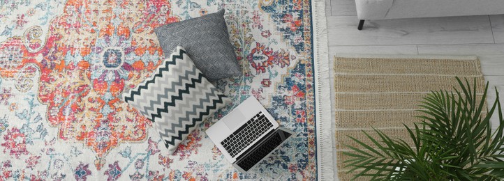 Image of Stylish living room with beautiful carpet, laptop and pillows on floor, above view. Banner design