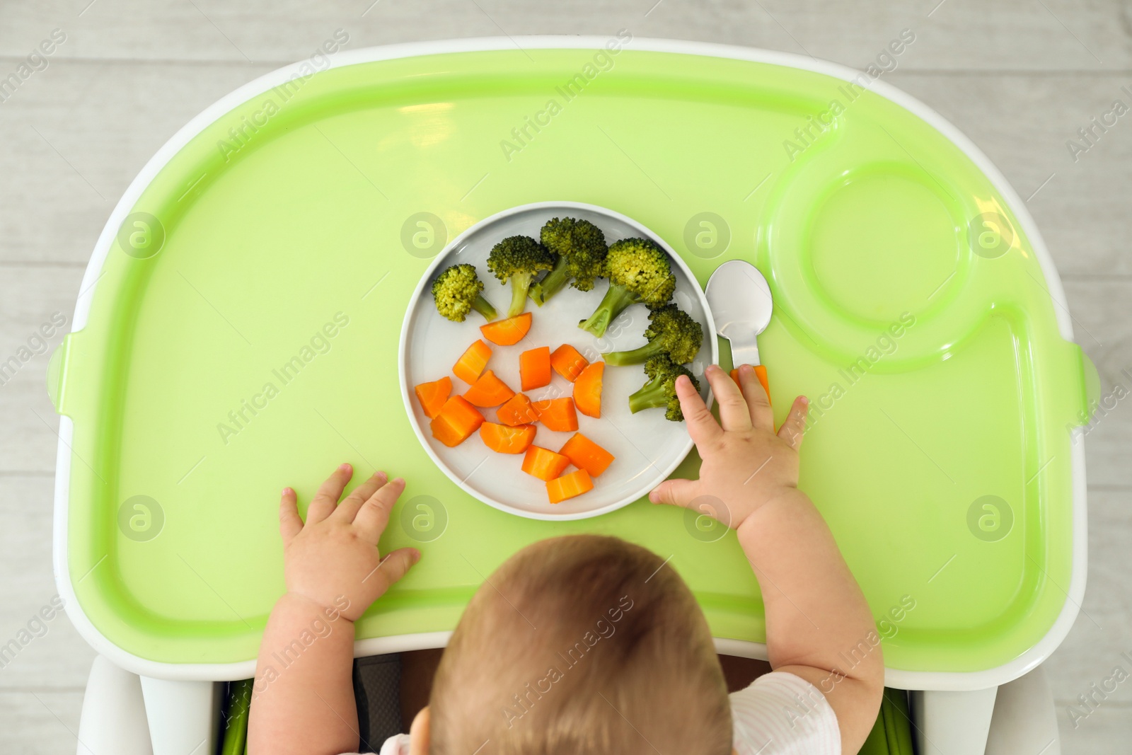 Photo of Cute little baby eating healthy food, top view