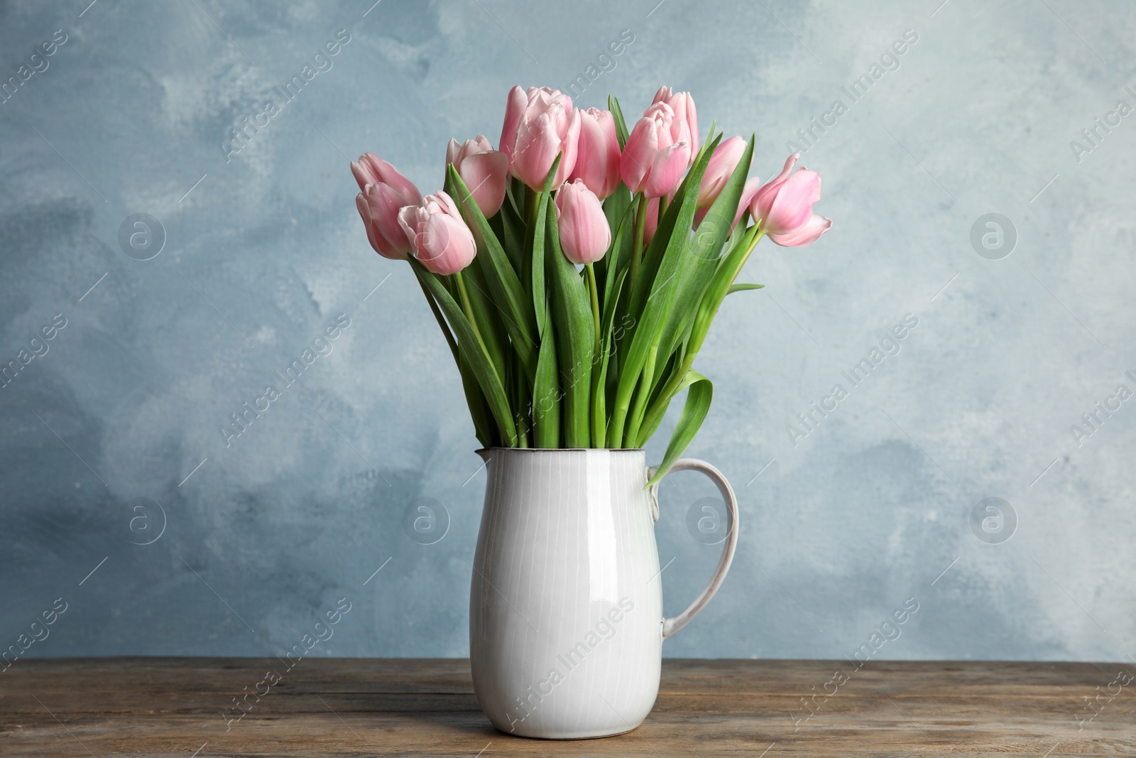 Photo of Beautiful pink spring tulips in vase on wooden table