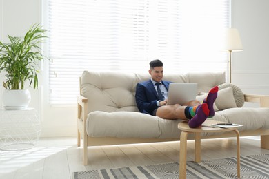 Photo of Businessman in jacket and underwear working on laptop at home