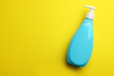 Bottle of liquid soap on yellow background, top view. Space for text