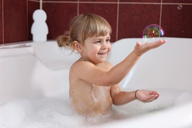 Happy girl having fun in bathtub at home