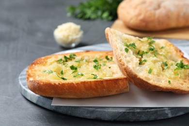 Photo of Slices of delicious toasted bread with garlic and herbs on grey table, closeup