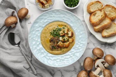 Photo of Delicious cream soup with mushrooms and croutons on white marble table, flat lay