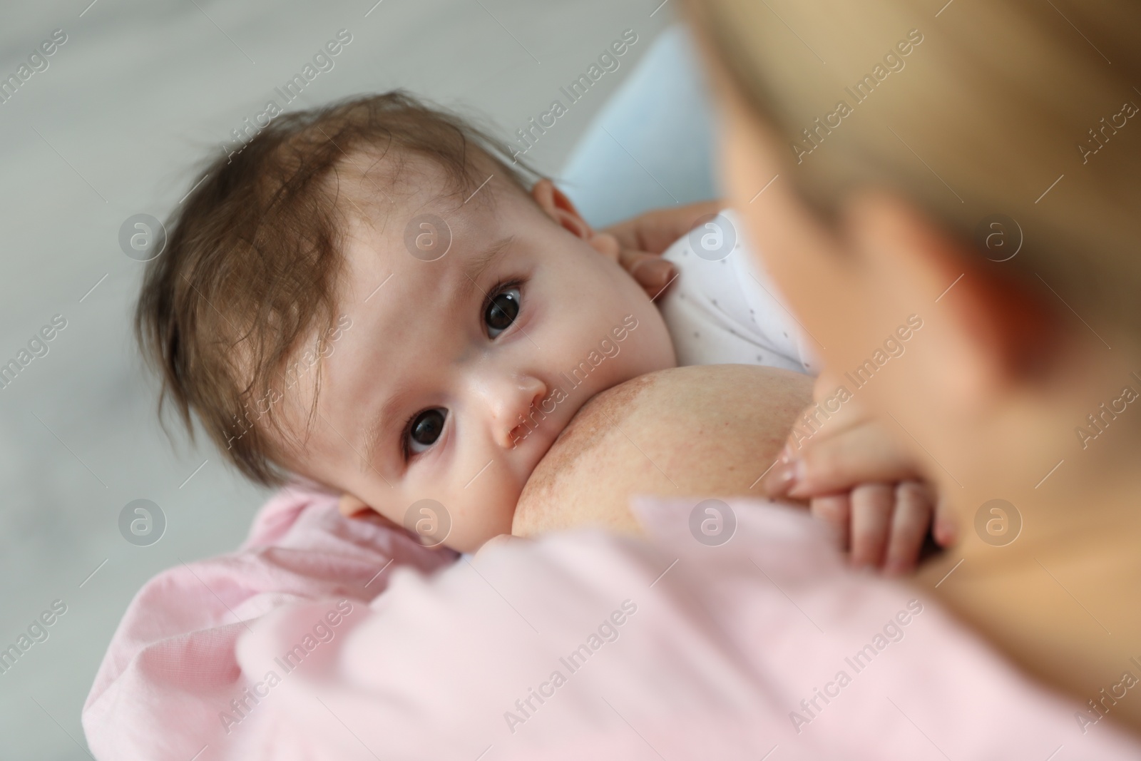 Photo of Young woman breastfeeding her baby at home, closeup