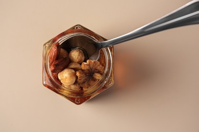 Photo of Jar with different nuts and honey on light table, top view