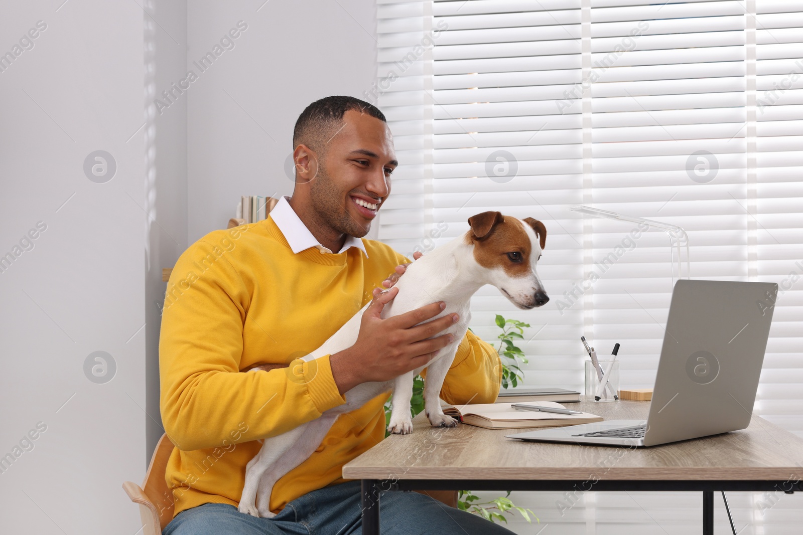 Photo of Young man with Jack Russell Terrier at desk in home office