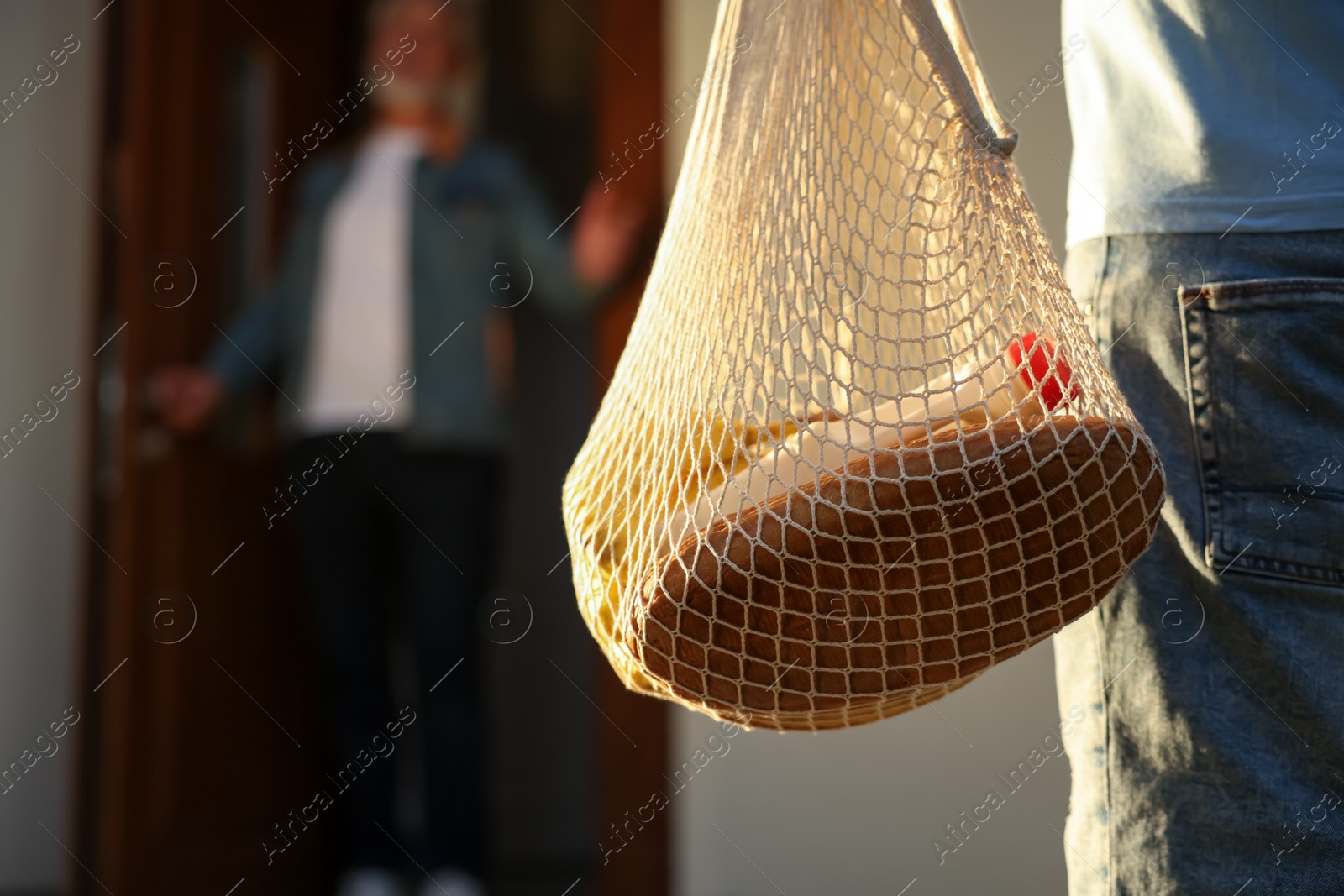 Photo of Man with net bag of products helping his senior neighbour outdoors, closeup