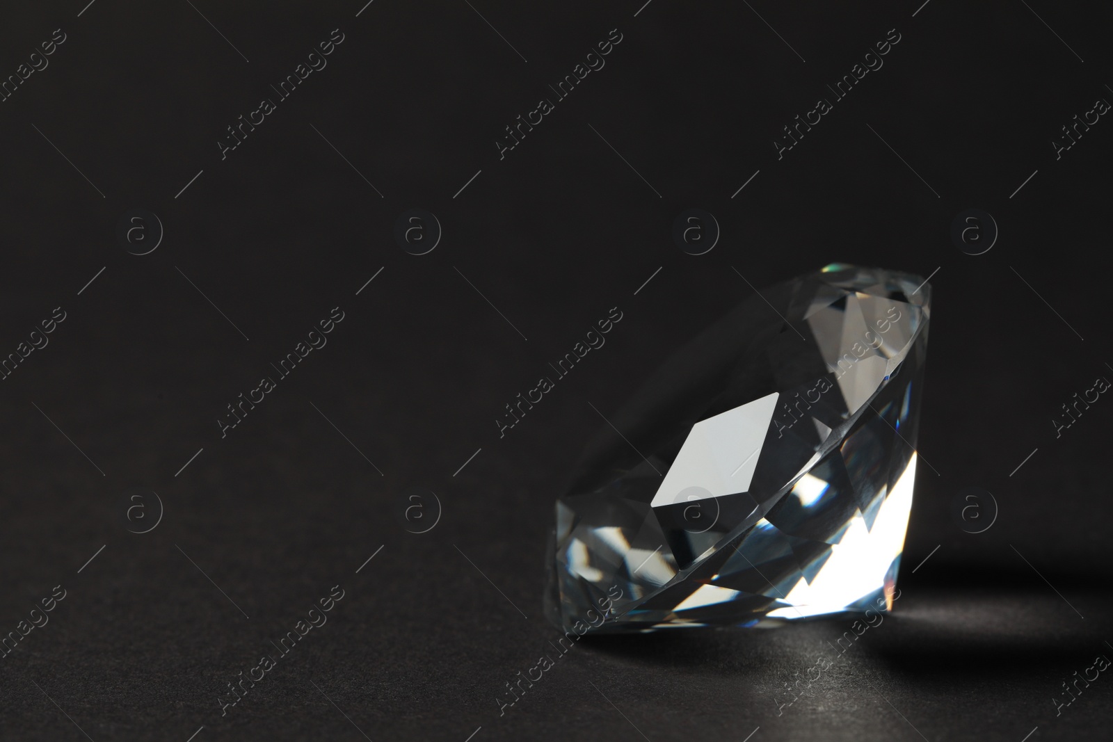 Photo of Beautiful dazzling diamond on dark background, closeup. Space for text