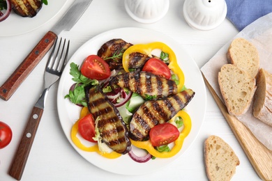 Photo of Delicious salad with roasted eggplant served on white wooden table, flat lay