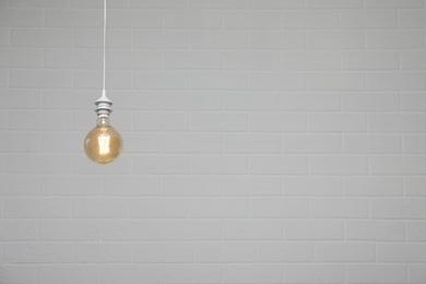 Photo of Lamp bulb near brick wall. Space for text