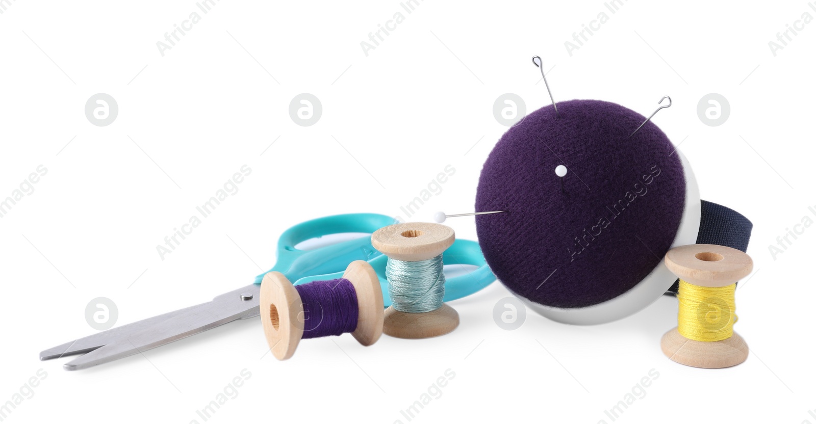 Photo of Pincushion, sewing needles, pins, spools of threads and scissors isolated on white