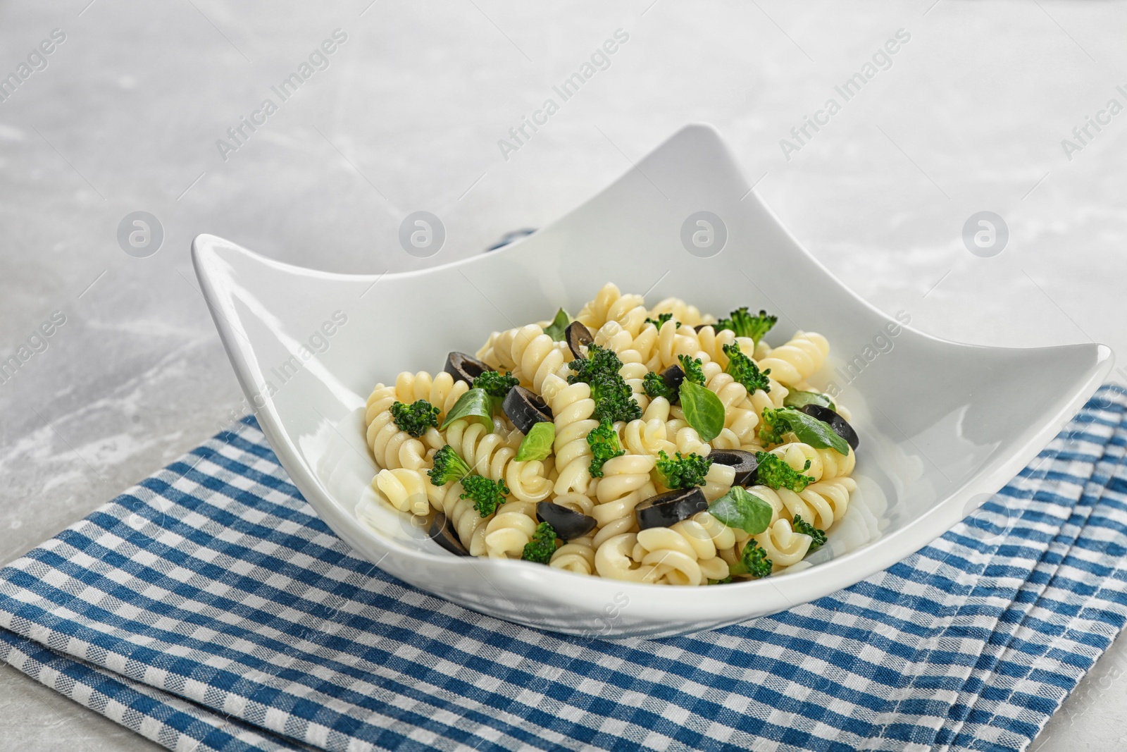 Photo of Tasty pasta salad with black olives  on table