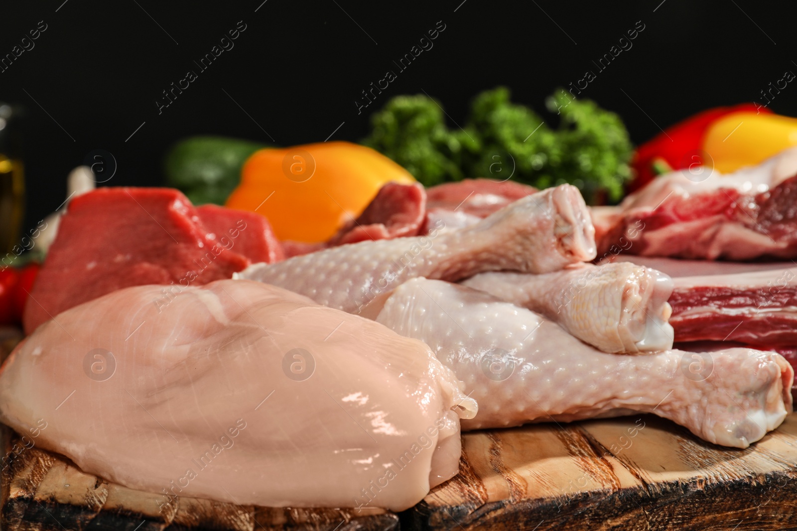 Photo of Wooden board with fresh raw meat on table against dark background